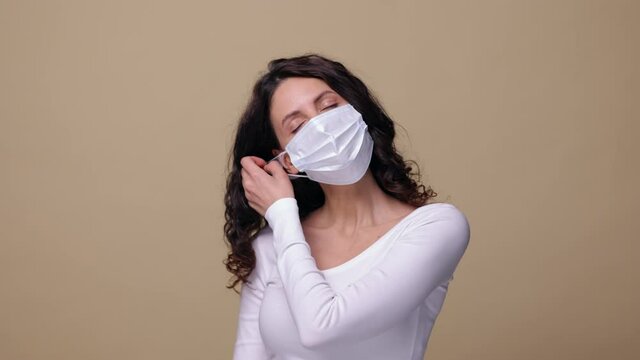 Portrait of happy woman taking off protective medical mask with smile of relief after end of coronavirus epidemic. Millennial female return to new normal life without covid-19 pandemic and quarantine