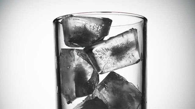 Ice cubes fall into a glass