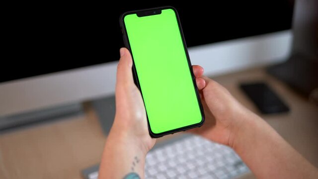 Business woman using smartphone, shopping online, viewing green screen on mobile phone using chroma key or green screen browsing online, watching social media. Close up hands with computer background
