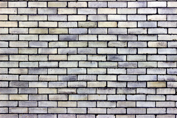 A pale light yellow brick wall with shades of blue