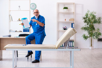 Old male doctor taking notes in the clinic