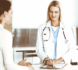 Doctor woman at work in hospital excited and happy of consulting female patient. Blonde physician...