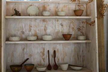 ceramic plates, bowls and stirring tools and spoon in a wooden cupboard