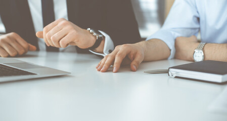 Unknown business people using laptop computer at the desk in modern office. Businessman or male entrepreneur is working with his colleague. Teamwork and partnership concept