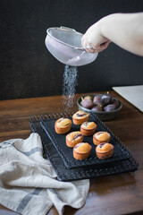 Fresh baked fig friand muffins on tray with sugar outline and cooking utensils