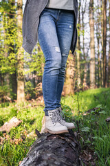 Hiking in forest. Woman wearing jeans and standing on tree trunk at woodland. Active lifestyle in nature