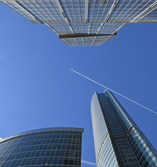 Obraz na płótnie Canvas Plane is flying in blue sky over skyscrapers of Moscow International Business Center in spring