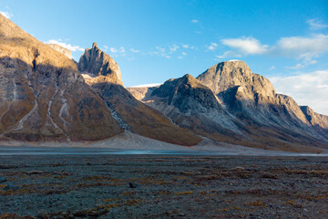 Sunset at the end of a sunny summer day in a remote arctic valley of Akshayuk Pass, Baffin Island, Canada. Last rays of sunlight light up surrounding peaks