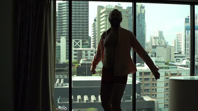 Happy fit man in underwear dancing by window at home