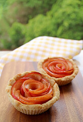 Closeup a Pair of Tasty and Healthy Mini Apple Rose Tartlets with Blurry Green Foliage in the Backdrop
