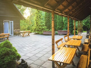 Obraz premium Holiday villa house yard with wooden tables and greenery in Lithuania countryside.