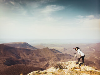 Side view young brunette caucasian woman travel photographer shooting landscape photo outdoor. New millennial photographers shooting landscapes on field.