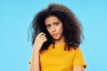 woman with curly hair in yellow t-shirt here studio blue background