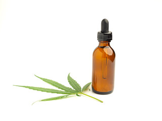 A bottle of cannabis oil extracts and green marijuana leaves isolated on a white background. Medical cannabis concept