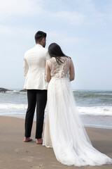 Fototapeta na wymiar Happy bride and groom holding hands and walking on a beach 