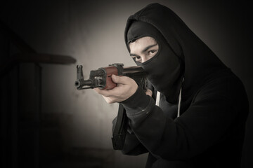 Terrorist hold a pistol gun aiming eye contact with blurred background.