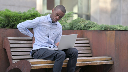 African Man with Back Pain using Laptop Outdoor 