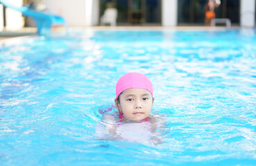 Fototapeta na wymiar Asian child cute or kid girl smile wearing swimming suit on school swimming pool and happy fun in water park for learn and training swim on kick board or refreshing relax to exercise on summer holiday