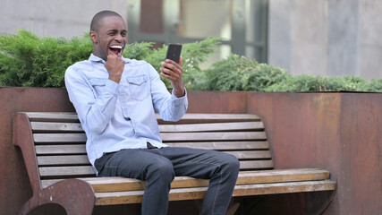 Ambitious African Man Celebrating Success on Smart Phone