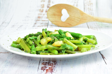 Asparagus with prawns, a touch of spices, oregano and olive oil, served on a white plate. 
