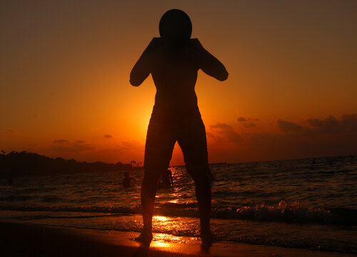 Silhouette of a young man wearing a hat on the seashore at sunset, horror images