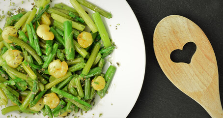 Plate of asparagus with prawns, a touch of spices and olive oil, slate stone background. Zenith view.