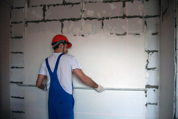 work on finishing the walls with mixtures of plaster and putty when building a house. builder...