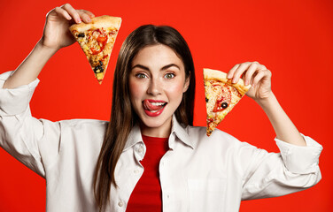 Happy girl licks lips and shows two slices of delicious pizza food delivery order, cannot wait to...