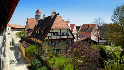 Aussicht von Stadtmauer in Nördlingen auf Stadttor und die Altstadt mit Fachwerkhaus bei blauem Himmel