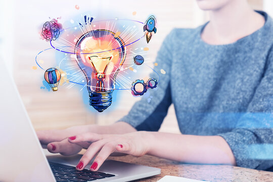 Young woman working on laptop. Colorful lightbulb as a concept o
