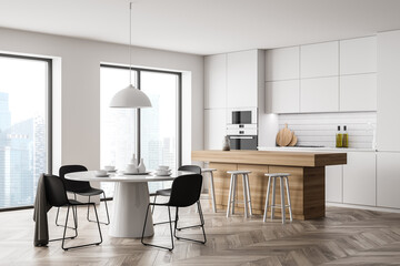 Light kitchen interior with round dining table and kitchen set near window