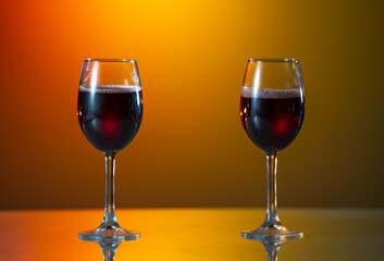 two glasses are standing on the background. Close-up of filling wine glass with red wine