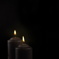 Fototapeta na wymiar Two black burning candles on black