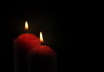 Two black burning candles on black