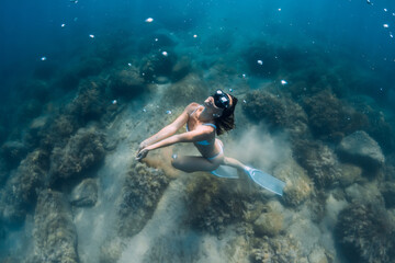 Fototapeta na wymiar Freediver woman glides on deep sea. Free diver with fins posing underwater in ocean