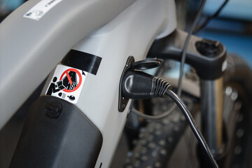 Charging electric bicycle. Charger plugged in to an ebike. Environmentally friendly transport. 