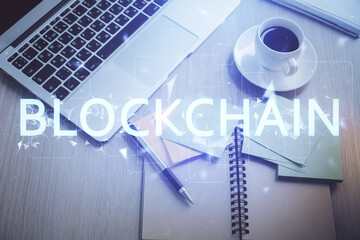 Blockchain theme hologram drawings over computer on the desktop background. Top view. Double...