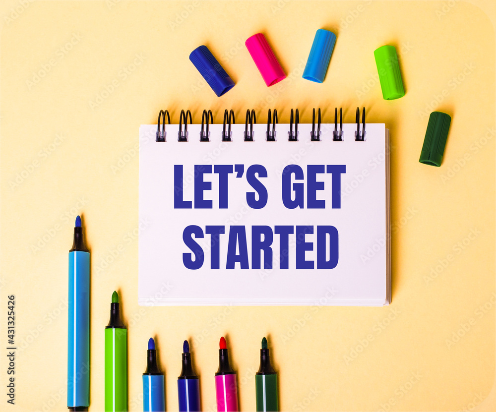 Poster the words let is get started written in a white notebook on a beige background near multi-colored ma