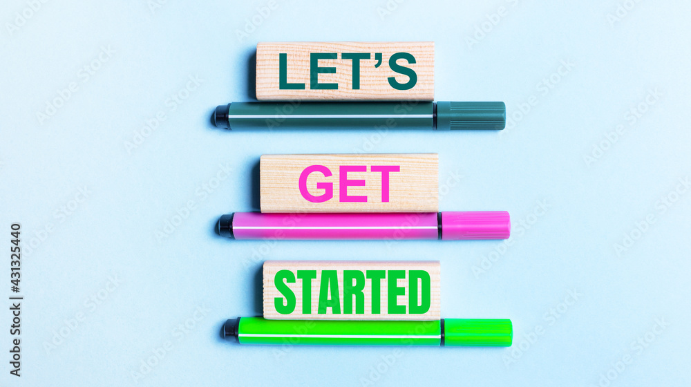 Aufkleber on a light blue background, there are three multi-colored felt-tip pens and wooden blocks with the l