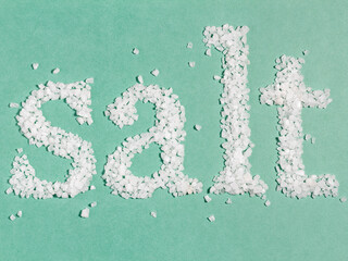 Word "Salt" is made of coarse sea salt. Minimal creative background.