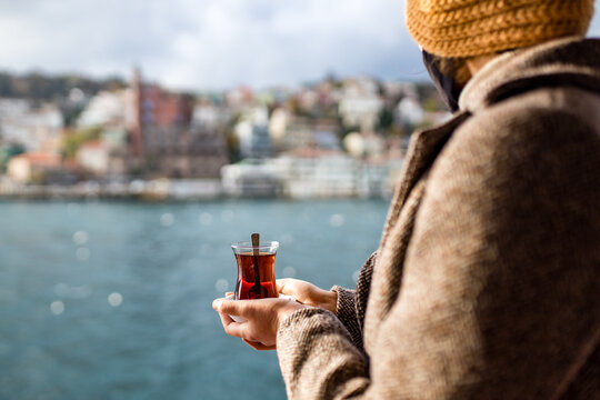 woman drinking Turkish tea in the front, bosphorus bay in the background