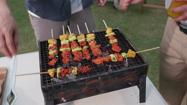 Happy Asian family having a barbecue-BBQ party together in the garden at home. New normal family lifestyle and happy family funny activity at home