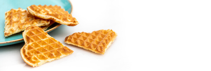 Heart shaped waffles standing scattered in green plate on white marble table