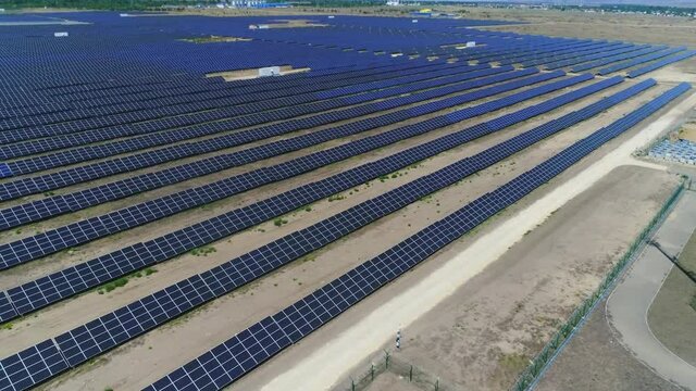 Slow flight over rows of solar panels in summer