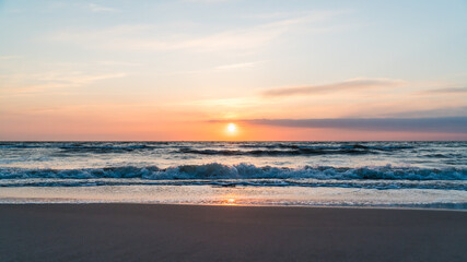 Wide shot of orange sunrise over the ocean at the beach on the German island Rügen at the baltic sea