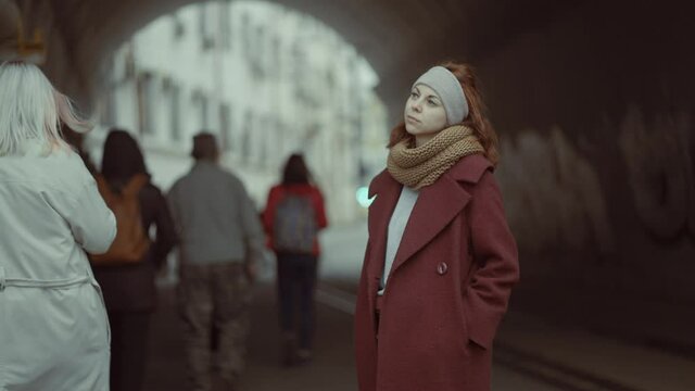 sad girl standing on a city avenue among people