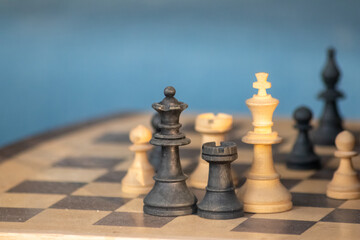 Wooden chess figures on antique chess table show the competitive chess game with strategic and intelligent battles to avoid checkmate with wise decisions to defeat the opponent as challenge victory