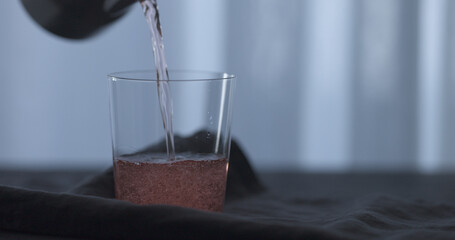 Fototapeta na wymiar pour rose drink into tumbler glass on linen cloth