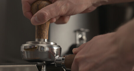 man tamping freshly ground coffee in portafilter