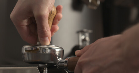 man tamping freshly ground coffee in portafilter